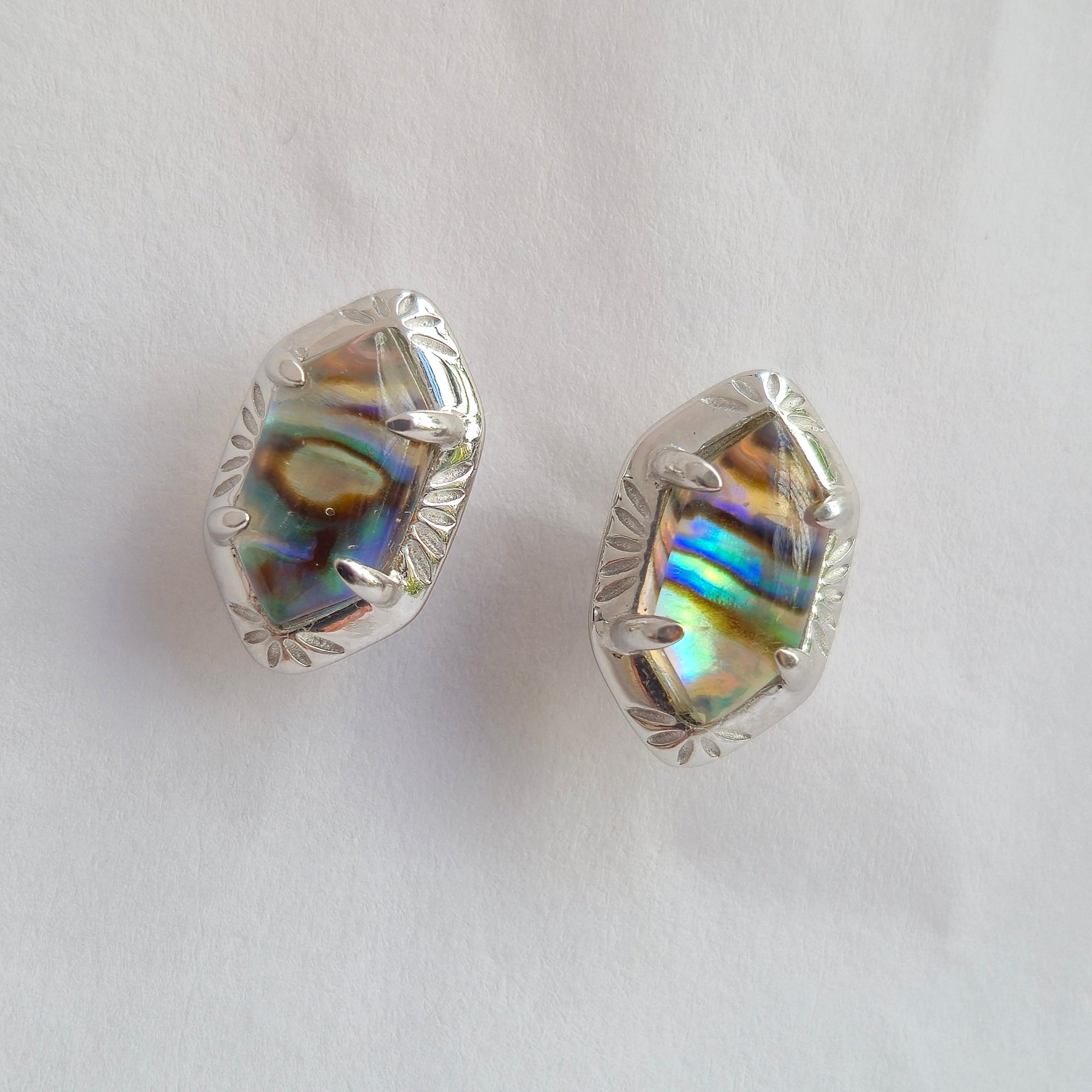 Silver earrings with colorful gemstones on a light gray background
